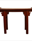 Close-up of red patina altar table with curved edges, scroll handles, and decorative legs in red finish.