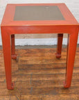 Red side tables with inset tile tops, wood flooring, white brick wall background.