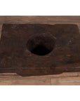 Brown wooden Indonesian planter with large circular hole, rustic design, on wooden floor indoors.