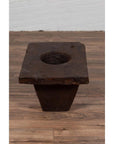 Brown wooden planter with large circular hole, antique Indonesian, early 20th century, on wooden floor indoors.