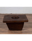 Brown wooden planter, antique Indonesian style, on a wooden floor indoors.