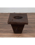 Brown wooden planter, antique Indonesian style, on a wooden floor beside a white wall indoors.