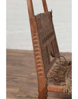 Close-up of brown wooden chair with rope seat and weathered finish on wooden floor indoors.