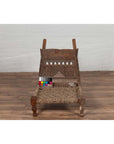 Brown wooden low chair with rope seat and weathered finish on a wooden floor indoors.