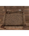 Brown wooden low chair with rope seat and weathered finish on a wooden floor.