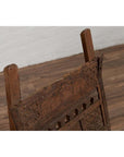 Close-up of brown wooden chair with rope seat, weathered finish, on wood floor next to a white brick wall indoors.