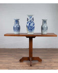 Blue and white ceramic vases on rustic Indonesian wooden console table with single plank top and pedestal base.