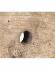 Close-up of brown weathered wooden ox cart wheel from Thailand on black painted base, showing grain and central hole.