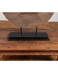 Brown wooden ox cart wheel on black painted base, displayed on a wooden table.