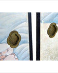 Close-up of two brass handles on vintage Japanese 2-panel screen with fictional character designs.
