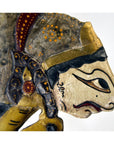 Close-up of three wooden Wayang Kulit Indonesian shadow puppets with intricate patterns and painted details.