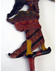 Close-up of brown wooden Wayang Kulit shadow puppets, focus on leg with curly-toed shoe.
