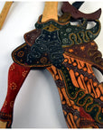 Close-up of red, orange, green, and black wooden Wayang Kulit shadow puppets.