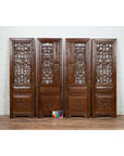 Set of four brown carved elm screen panels with fretwork, foliage, and floral motifs on a white brick wall.