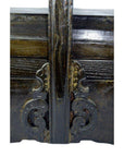 Close-up of dark wood elm box with ornate carved scrollwork and central beam detail.