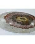 Brown, red, and tan stone Shiva Lingam with smooth oval patterns, close-up view.