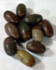 Brown and greenish smooth oval Shiva Lingam stones, stone material, close-up on white background.