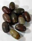 Brown and greenish smooth oval Shiva Lingam stones, stone material, close-up on white background.