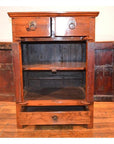 Wooden side cabinet with two open doors, two top drawers, and a bottom drawer on a wooden floor.
