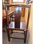Dark wood side chair with tall back and square seat next to dining table in carpeted room.