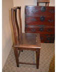 Brown wood side chair with curved backrest beside a vintage red wood chest with black metal handles and locks.