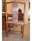 Wooden side chair with a tall, curved backrest and wide central panel in a carpeted room.