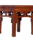 Natural wood side table with decorative carved legs and geometric underside, close-up view.