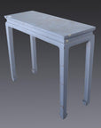 Close-up of vintage light blue wooden side table with four horse hoof feet and worn paint, against a gray background.