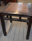 Brown burl wood side table with straight legs and flat top on a light wooden floor.