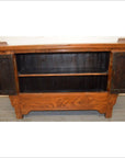 Wood sideboard with everted flanges, two open doors showing an interior shelf, visible natural wood grain.