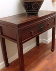 Black and gold side console table with horse hoof legs, metal accents, drawer, decorative bowl on top.