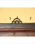 Close-up of a signboard mounted on a yellow wall above dark wooden trim.