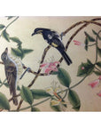 Silk painting with two birds perched on a branch with green leaves and pink blossoms on a light background.