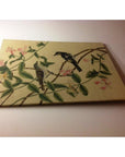 Framed silk painting with colorful birds on branches, pink flowers, and green leaves on a light background.