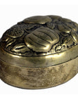 Close-up of silver plate jewelry box with ornate embossed floral and leaf design, oval shape, on lid.