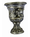 Silver plate urn with decorative leaf accents and cherub design on ornate base, close-up.