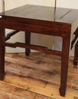 Dark polished wood square table with angled horse hoof feet, set on a wooden floor.