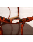 Close-up of a brown bamboo and elm horseshoe-back armchair with visible white label on the armrest. 19th century.