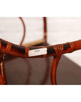Close-up of a brown bamboo and elm horseshoe-back armchair with visible white label on the armrest. 19th century.