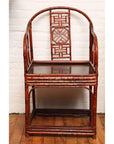 Brown bamboo and elm horseshoe-back armchair on wooden floor against a white wall indoors.