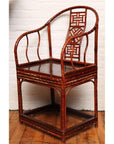 Brown bamboo and elm horseshoe-back armchair on wooden floor beside a white brick wall indoors.