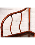 Close-up of brown bamboo and elm horseshoe-back armchair, 19th century, indoors against a white brick wall.