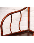 Close-up of brown bamboo and elm horseshoe-back armchair, 19th century, indoors against a white brick wall.