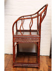 Brown bamboo and elm horseshoe-back armchair placed indoors by a white brick wall and wooden floor.