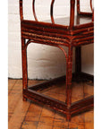 Close-up of brown bamboo and elm horseshoe-back armchair on wood floor against white brick wall.
