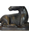 Bronze sitting deer sculpture on oval base, head turned left, close-up view, very good condition.