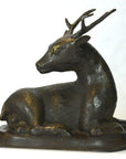 Bronze sitting deer sculpture with detailed antlers on oval base, close-up view, very good condition.
