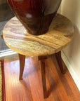 Brown mango wood round table with 19" wood-grained top and three legs, shown for corner or decor use.