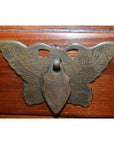 Brass butterfly-shaped drawer pull with ornate wing design on small side cabinet.