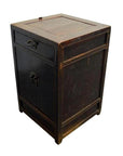 Close-up of dark wood antique carved side cabinet with brass medallion, one drawer, and door, lightly worn finish.
